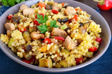 Kuskus, sebze (kabak, patlıcan, havuç, tatlı biber, soğan), koyu ahşap arka plan üzerinde tavuk parçaları ile hafif sağlıklı diyet salata.