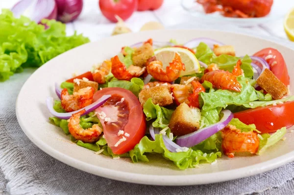 Легкий смачний салат з м'ясом раку, креветками, салатом, часниковими грінками, помідорами, червоною цибулею — стокове фото