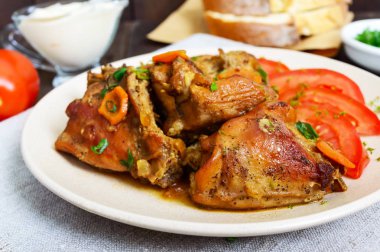 Tavşan parçalar ile seramik tabak içinde koyu ahşap arka plan üzerinde taze domates ihtiva eder. Diyet menüsü.