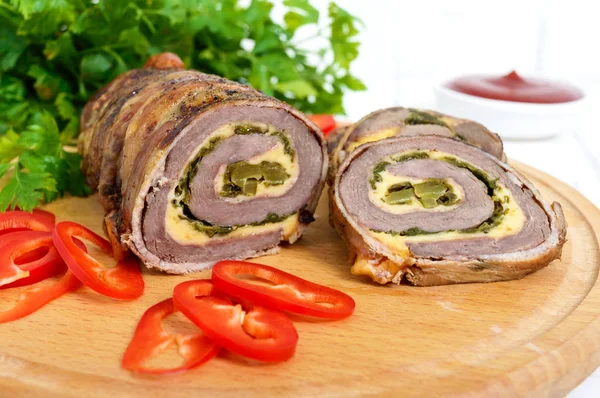 Pastırma Beyaz ahşap zemin üzerinde domates soslu köfte (rulo) peynir, ıspanak, salatalık turşusu ile sarılı. Tatil menüsü.