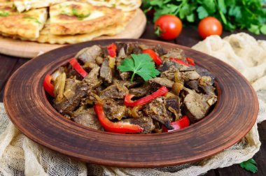 Karaciğer ve koyu ahşap bir masa üzerinde bir kil kase tatlı biber sıcak salata. Kızarmış Karaciğer.