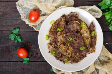 Kızarmış domuz karaciğer koyu ahşap arka plan üzerinde bir tabakta parçaları.