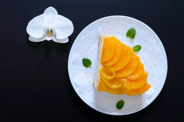 Sulu şeftali ile hassas sufle. Büyük lezzetli oyuncağı bir beyaz plaka ve siyah bir zemin üzerine beyaz orkide çiçek. Üstten Görünüm