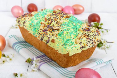 Paskalya ekmek kulich sır ile renkli şeker sprinkles. Renkli boyalı yumurta. Beyaz ahşap zemin üzerinde güzel geleneksel Hıristiyan Paskalya yemek.