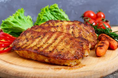 Sulu biftek yeşil ve sebzeler bir ahşap tepsi ile. Büyük bir parça domuz eti bonfile ızgara.