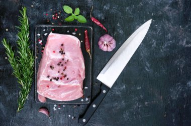 Çiğ et. Domuz baharatlar ve tuz bir kesme tahtası siyah bir arka plan üzerinde büyük bir parçası.