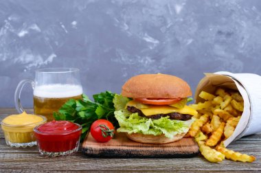 Sulu hamburger, patates kızartması, soslar, bira ahşap arka plan üzerinde. Fast food. Sokak gıda.