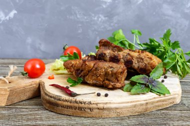 Kızarmış domuz kaburga bir kesme tahtası üzerinde yeşillikleri ile.