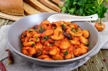 Haşlanmış bakla domates soslu yakın çekim, otlar ve baharatlar ile dilim çavdar ekmeği ahşap masa üzerinde. Paskalya menü. Vegan yemek.