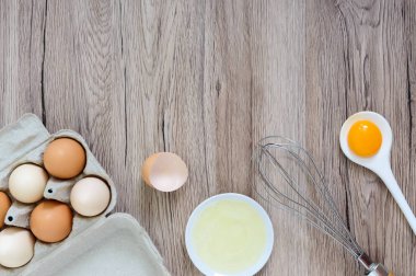 Ahşap rustik arka plan üzerinde taze çiftlik yumurtaları. Yumurta beyazı ve sarısı, yumurta kabukları kırık ayrılmış. Yumurta çırpma teli ile kırbaçlanan. Tavuk yumurtası gıda hazırlanması. Üstten Görünüm. Yukarıdan görüntülemek.