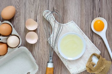 Ahşap rustik arka plan üzerinde taze çiftlik yumurtaları. Yumurta beyazı ve sarısı, yumurta kabukları kırık ayrılmış. Yumurta çırpma teli ile kırbaçlanan. Tavuk yumurtası gıda hazırlanması. Üstten Görünüm. Yukarıdan görüntülemek.