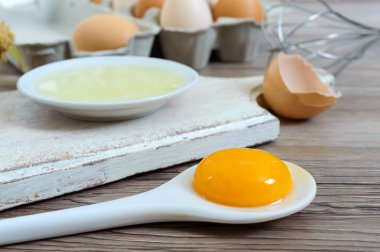 Ahşap rustik arka plan üzerinde taze çiftlik yumurtaları. Yumurta beyazı ve sarısı, yumurta kabukları kırık ayrılmış. Yumurta çırpma teli ile kırbaçlanan. Tavuk yumurtası gıda hazırlanması.