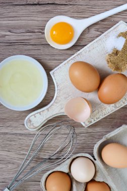 Ahşap rustik arka plan üzerinde taze çiftlik yumurtaları. Yumurta beyazı ve sarısı, yumurta kabukları kırık ayrılmış. Yumurta çırpma teli ile kırbaçlanan. Tavuk yumurtası gıda hazırlanması. Üstten Görünüm. Yukarıdan görüntülemek.