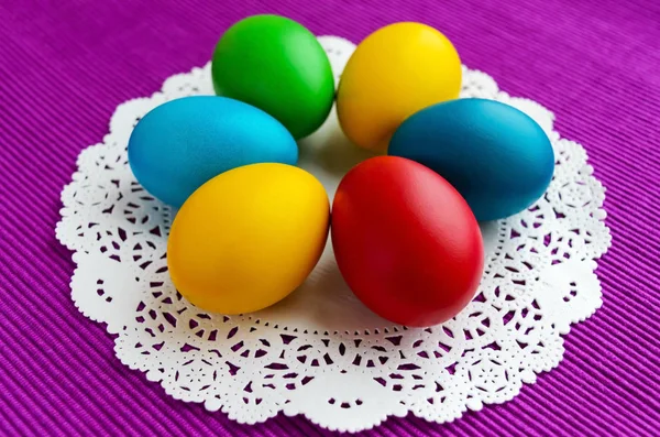 鮮やかな背景に白いナプキンにイースターの休日のためのカラフルな卵 — ストック写真