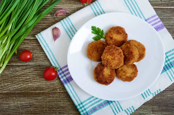 一张木桌上的陶瓷盘子里多汁的金色油炸肉饼 顶部视图 — 图库照片