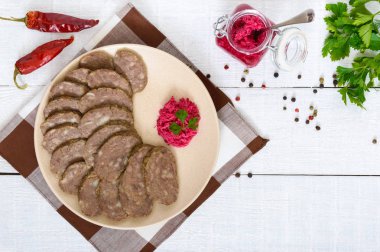 Ev Beyaz ahşap bir masa üzerinde karaciğer diyet sosis yapılmış. Sosis tabakta horseradish sos ile parçalar halinde kesin. Üstten Görünüm.