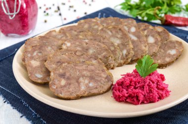 Ev Beyaz ahşap bir masa üzerinde karaciğer diyet sosis yapılmış. Sosis tabakta horseradish sos ile parçalar halinde kesilmiş.