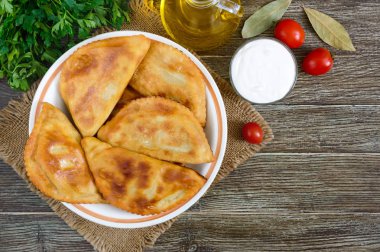 Ahşap bir masa üzerinde sulu altın chebureks. Geleneksel Türk-Moğol çanak. Sokak gıda. Bistro. Üstten Görünüm.