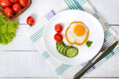 Sahanda yumurta beyaz ahşap zemin üzerinde taze sebze ile tatlı biber beyaz bir plaka üzerinde bir daire içinde. Lezzetli sağlıklı kahvaltı. Doğru beslenme.