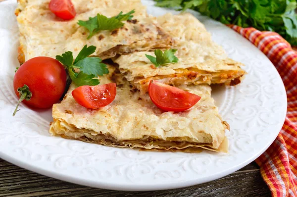 Pie, casserole pita with mushrooms, cottage cheese and cheese on a white plate on a wooden background. Layer Cake.