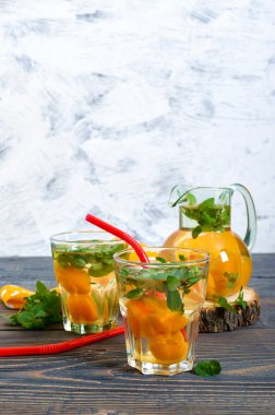 Yaz soğuk içecekler. Delicious içecek kayısı ve nane ahşap bir masa üzerinde gözlük ile yenileniyor. Komposto meyve. Seçici odak.