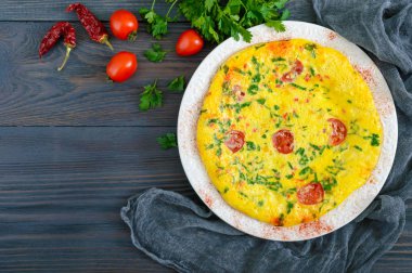 Frittata. Peynir, yeşil ve ahşap arka plan üzerinde beyaz bir tabakta domates ile İtalyan omleti. Üstten Görünüm.