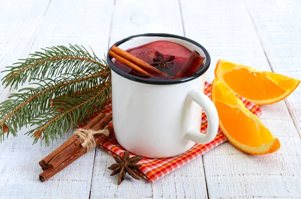 Hot mulled wine in a mug on a white wooden background. A traditional warming winter wine drink with aromatic spices.