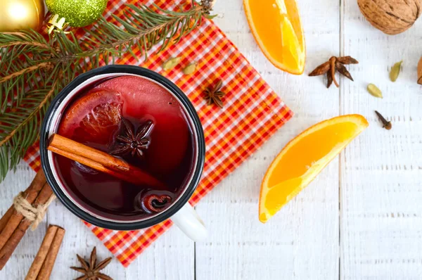 Hot mulled wine in a mug on a white wooden background. A traditional warming winter wine drink with aromatic spices.