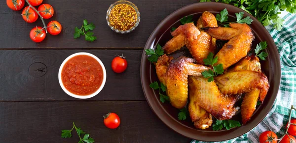 Baked chicken teriyaki wings in honey mustard sauce with adjika and mustard on dark wooden table.  Asian recipe. Rustic style. Top view. Flat lay.