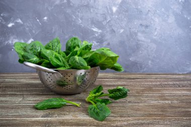 Tahta masadaki bir kasede taze ıspanak yaprakları. Faydalı, lezzetli, düşük kalorili sebzeler. Genç ıspanak filizleri. Keto diyeti.