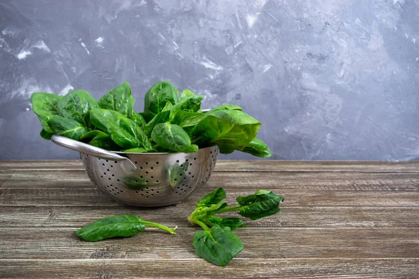 Tahta masadaki bir kasede taze ıspanak yaprakları. Faydalı, lezzetli, düşük kalorili sebzeler. Genç ıspanak filizleri. Keto diyeti.