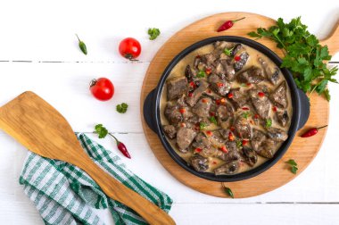 Beyaz ahşap arka planda kremalı soslu soğan ve mantarlı hindi ciğeri. Diyet menüsü. Üst görünüm.