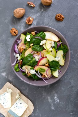 Ispanaklı, elmalı, kırmızı soğanlı, mavi peynirli, fındıklı lezzetli diyet fitness salatası. Düzgün beslenme. Hafif beton arka plan. Üst görünüm.