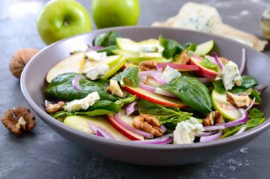 Ispanaklı, elmalı, kırmızı soğanlı, mavi peynirli, fındıklı lezzetli diyet fitness salatası. Düzgün beslenme. Hafif beton arkaplan