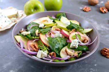 Ispanaklı, elmalı, kırmızı soğanlı, mavi peynirli, fındıklı lezzetli diyet fitness salatası. Düzgün beslenme. Hafif beton arkaplan