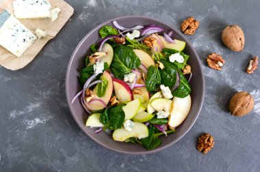 Ispanaklı, elmalı, kırmızı soğanlı, mavi peynirli, fındıklı lezzetli diyet fitness salatası. Düzgün beslenme. Hafif beton arka plan. Üst görünüm.