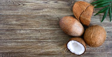 Hindistan cevizi. Hindistan cevizi, hindistan cevizi kabuğu ve ahşap arka planda yeşil yapraklar. Büyük kaçık. Kabuğunda tropik meyve hindistan cevizi. Spa mı? Yemek fotoğrafı. Fotoğraf arkaplanı. Doku tropikal meyvesi. Boşluğu kopyala.