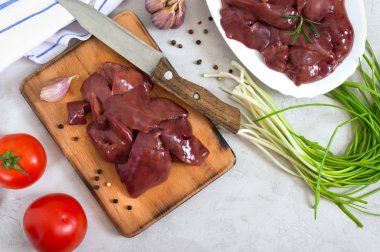 Kesme tahtasında çiğ tavuk ciğeri, masada bıçak. Offal. Pişirmeye hazır. Tabaklar karaciğerden. Üst görünüm.