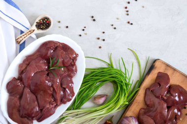 Kesme tahtasında çiğ tavuk ciğeri, masada bir kasede. Offal. Pişirmeye hazır. Tabaklar karaciğerden. Üst Manzara. Boşluğu kopyala