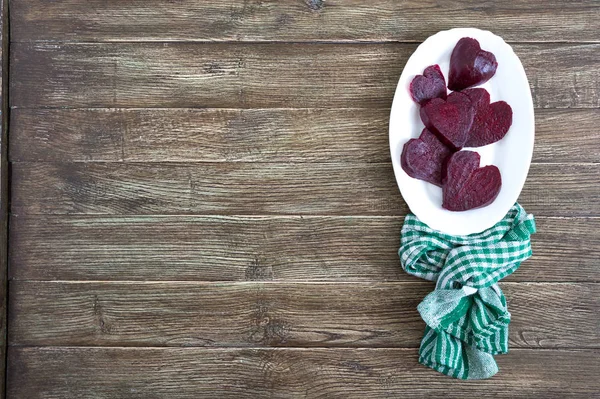 Slices of cooked beets in the shape of a heart on a white plate