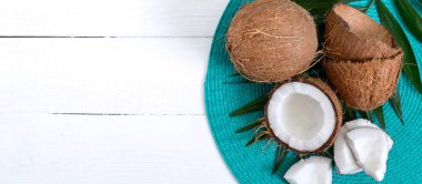 Hindistan cevizi. Beyaz ahşap arka planda tüm hindistan cevizi, kabuk ve yeşil yapraklar. Büyük kaçık. Kabuğunda tropik meyve hindistan cevizi. Kaplıca. Yemek fotoğrafı. Fotoğraf arkaplanı. Doku tropikal meyvesi. Boşluğu kopyala.