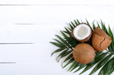 Hindistan cevizi. Beyaz ahşap arka planda tüm hindistan cevizi, kabuk ve yeşil yapraklar. Büyük kaçık. Kabuğunda tropik meyve hindistan cevizi. Kaplıca. Yemek fotoğrafı. Fotoğraf arkaplanı. Doku tropikal meyvesi. Boşluğu kopyala.