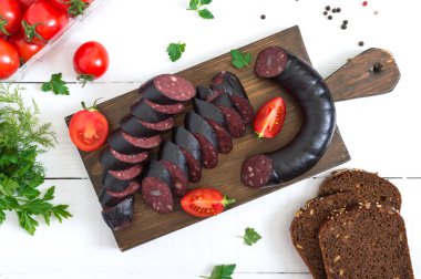 Morsilla, kanlı sosis. Beyaz arka planda tahta kesme tahtasındaki İspanyol kara pudingi parçaları. Paskalya menüsü. Üst görünüm