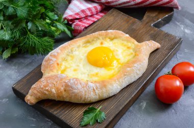 Adjarian 'da Khachapuri. Geleneksel Gürcü ve Ermeni mutfağı. Tahta bir tahtanın üzerinde, suluguni peyniri ve yumurta sarısı şeklinde açık bir turta.