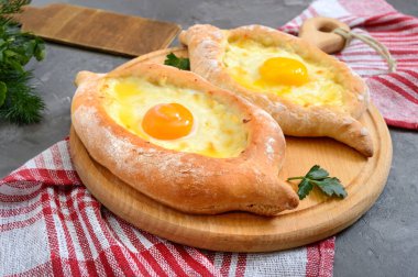 Adjarian 'da Khachapuri. Geleneksel Gürcü ve Ermeni mutfağı. Tahta bir tahtanın üzerinde, suluguni peyniri ve yumurta sarısı şeklinde açık bir turta.. 
