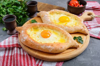 Adjarian 'da Khachapuri. Geleneksel Gürcü ve Ermeni mutfağı. Tahta bir tahtanın üzerinde, suluguni peyniri ve yumurta sarısı şeklinde açık bir turta.