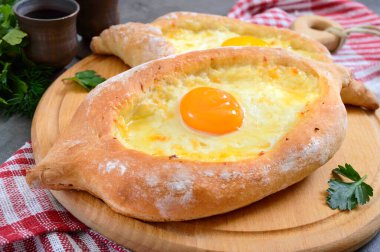 Adjarian 'da Khachapuri. Geleneksel Gürcü ve Ermeni mutfağı. Tahta bir tahtanın üzerinde, suluguni peyniri ve yumurta sarısı şeklinde açık bir turta.