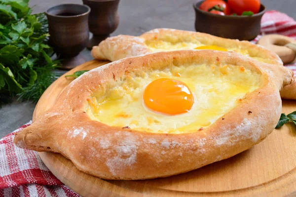 Adjarian 'da Khachapuri. Geleneksel Gürcü ve Ermeni mutfağı. Tahta bir tahtanın üzerinde, suluguni peyniri ve yumurta sarısı şeklinde açık bir turta. Üst görünüm