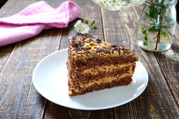 有坚果奶油的巧克力蛋糕放在木制桌子上 盘子里的一块蛋糕 — 图库照片