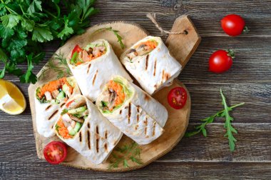 Taze tortilla paketleri tavuk, mantar ve taze sebzelerle ahşap tahtada. Meksika usulü tavuk. Lezzetli aperatif. Pita ekmeğinden tabaklar. Sağlıklı gıda konsepti.